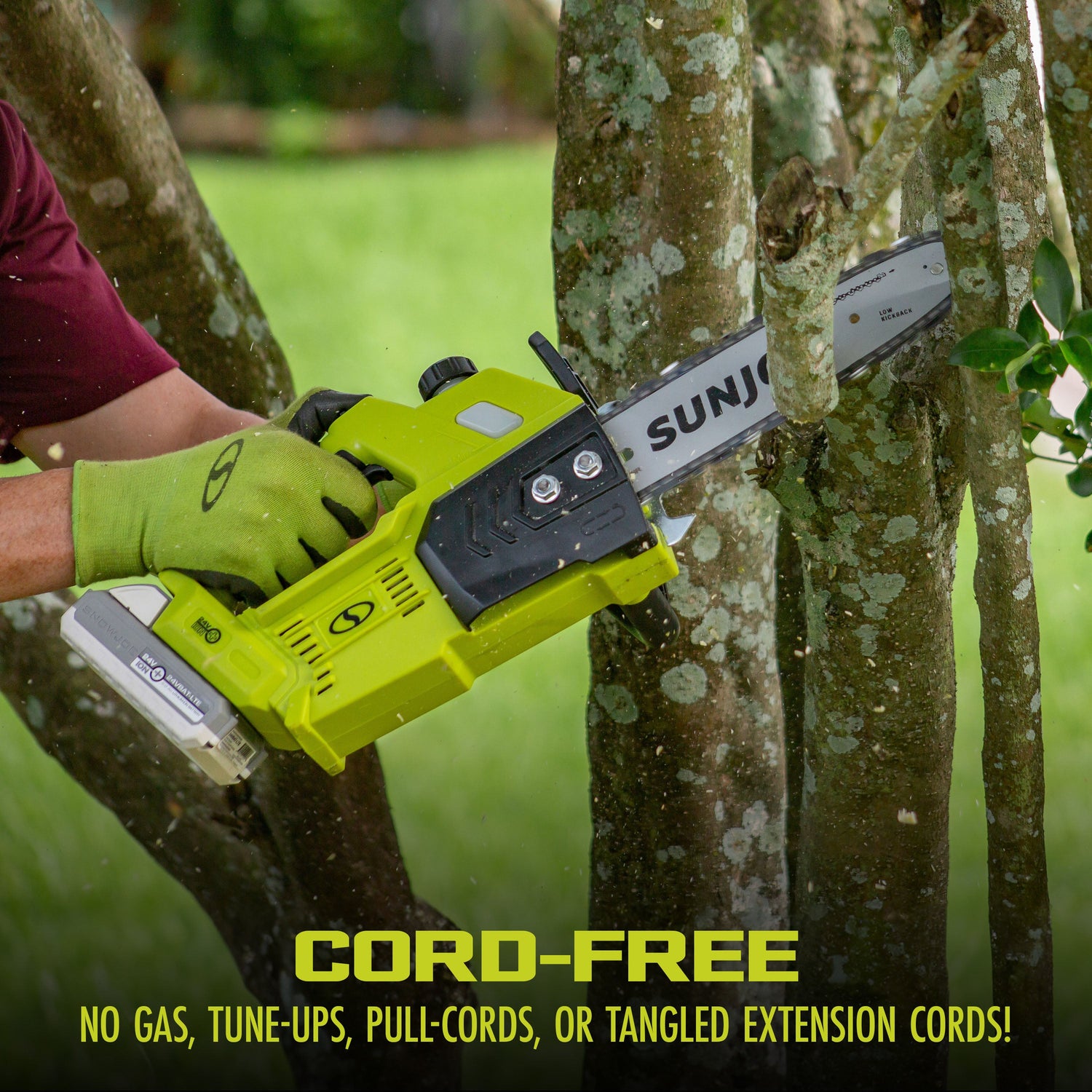 Person using a Sun Joe cordless chainsaw to trim a tree branch with a blurred green background.