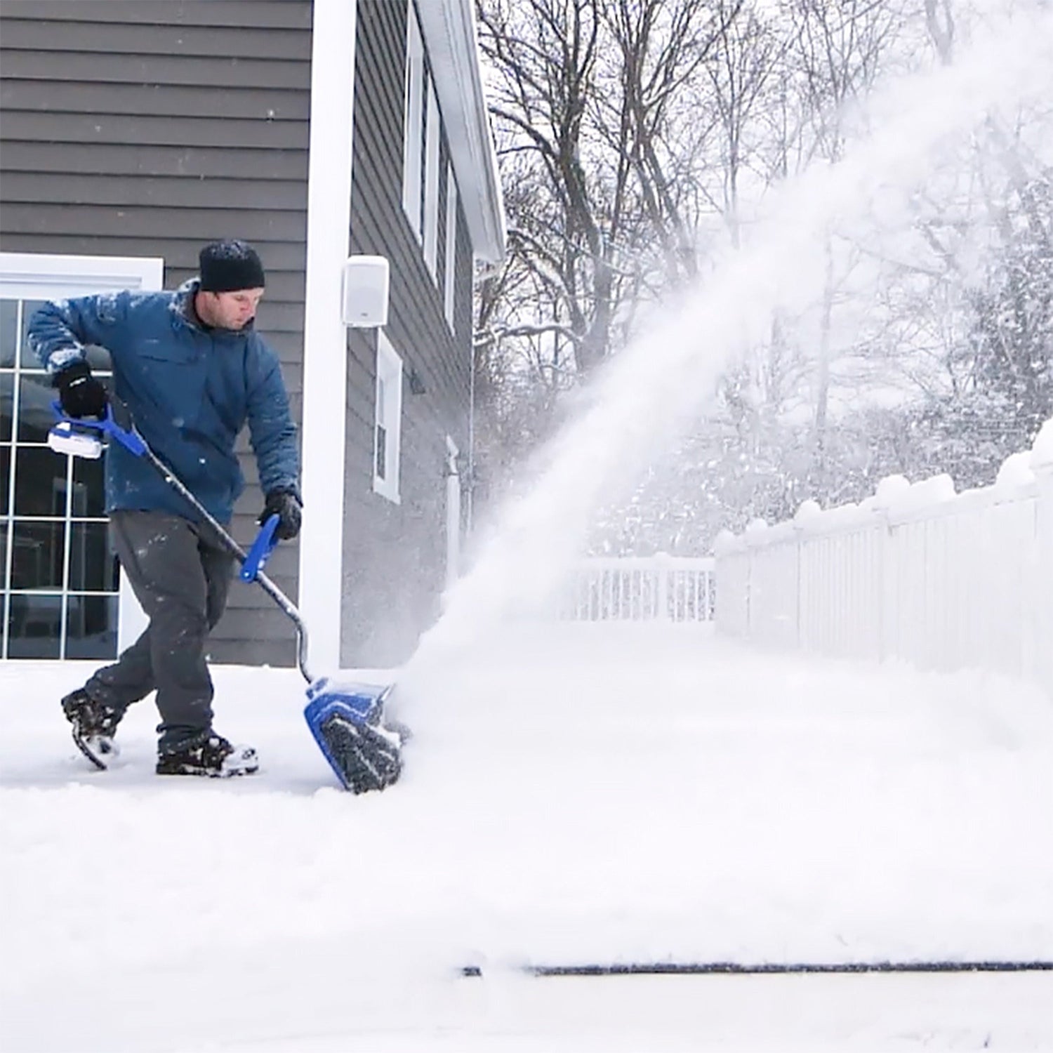 Person using a snow blower to clear snow outside a house