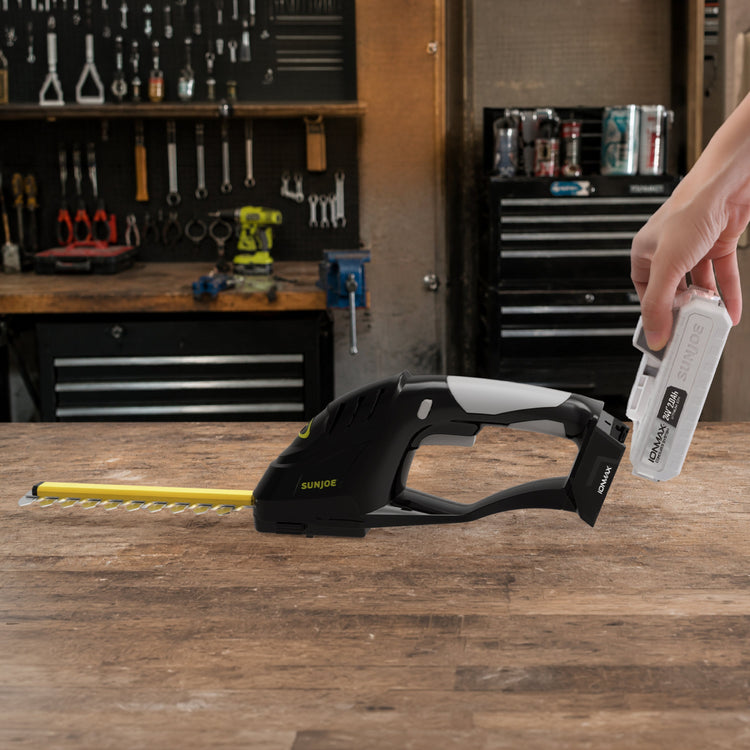 Hand holding a staple gun with staples on a workshop counter