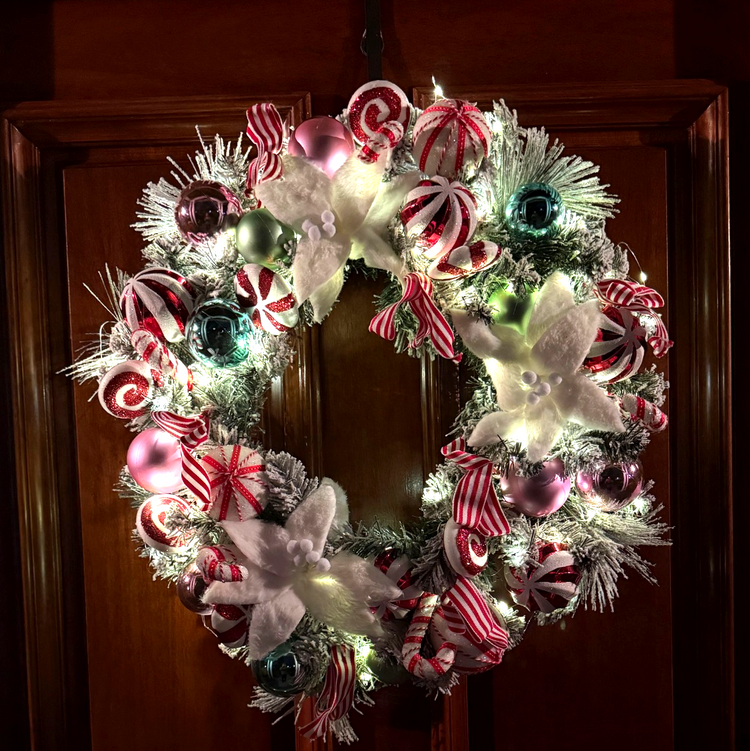 Decorative Christmas wreath with candy-themed decorations on a wooden door.