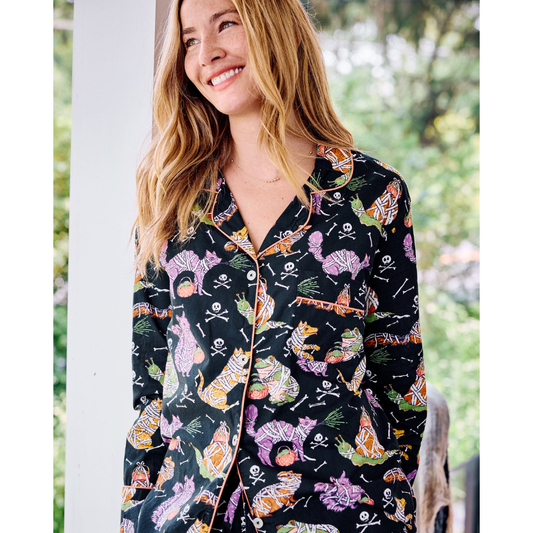Woman wearing a black pajama top with colorful cat pattern outdoors.