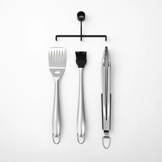 Black portable grill with cooking utensils on a white background
