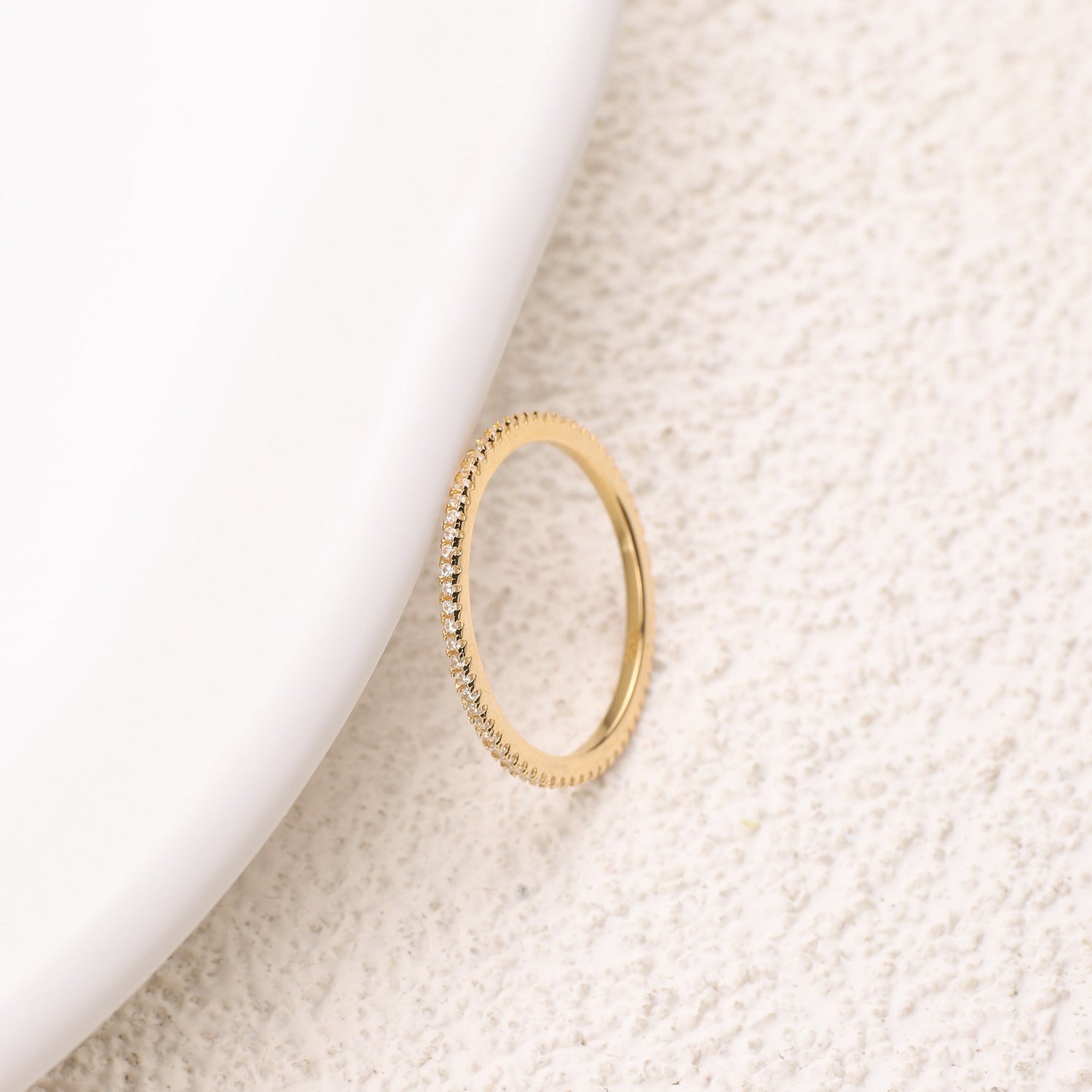 Gold ring on a textured beige surface