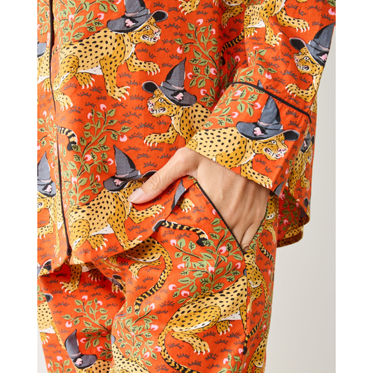 Woman wearing a patterned orange pajama set against a plain background