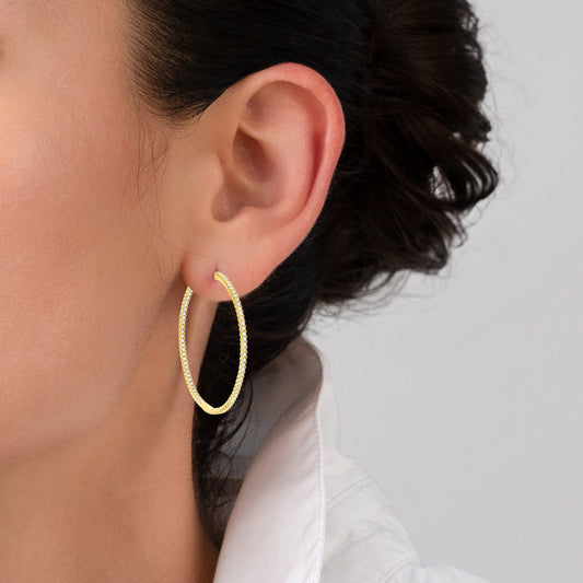 Gold hoop earrings with embedded diamonds on a white background