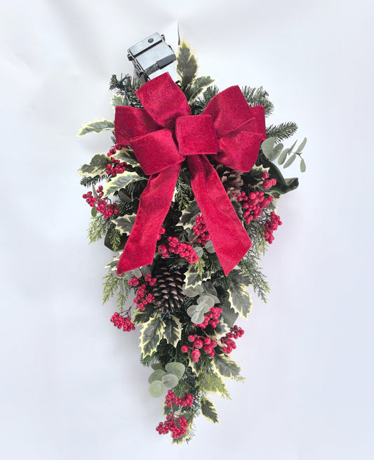 Christmas wreath with red berries, greenery, and a large red bow on a white background