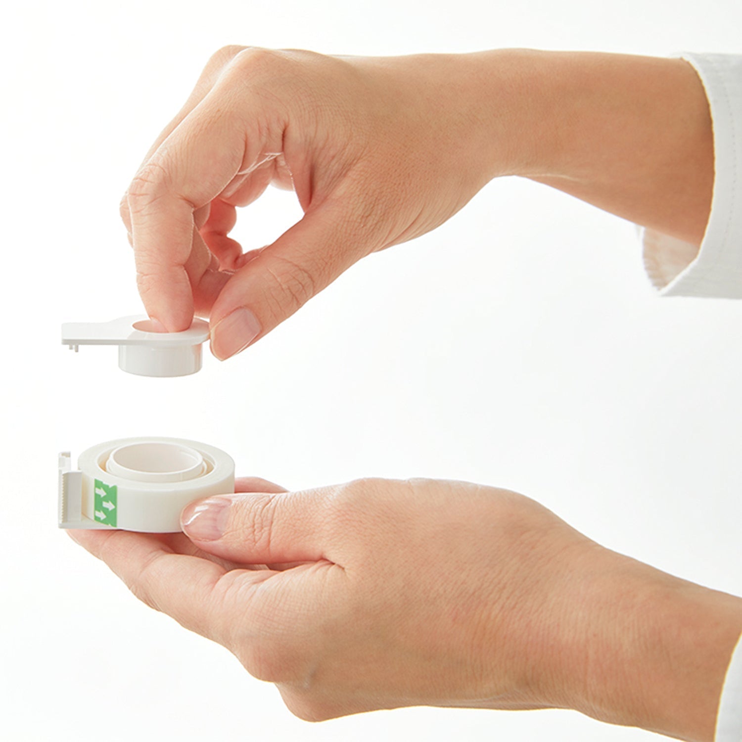 Person holding a roll of white tape with a small container on a white background