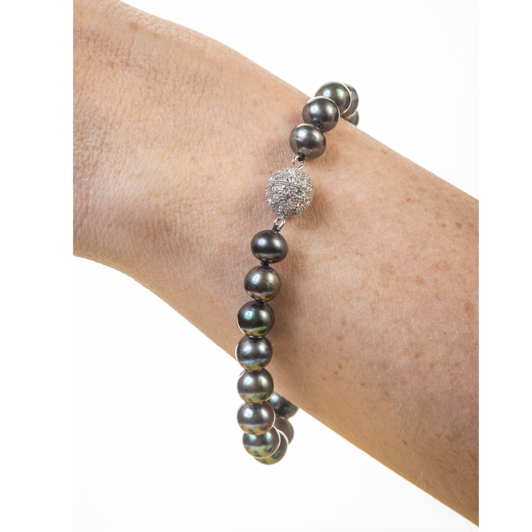Gray beaded bracelet on a wrist against a white background