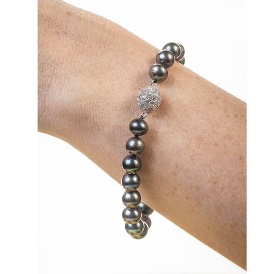 Necklace with dark pearls and a textured silver clasp on a white background