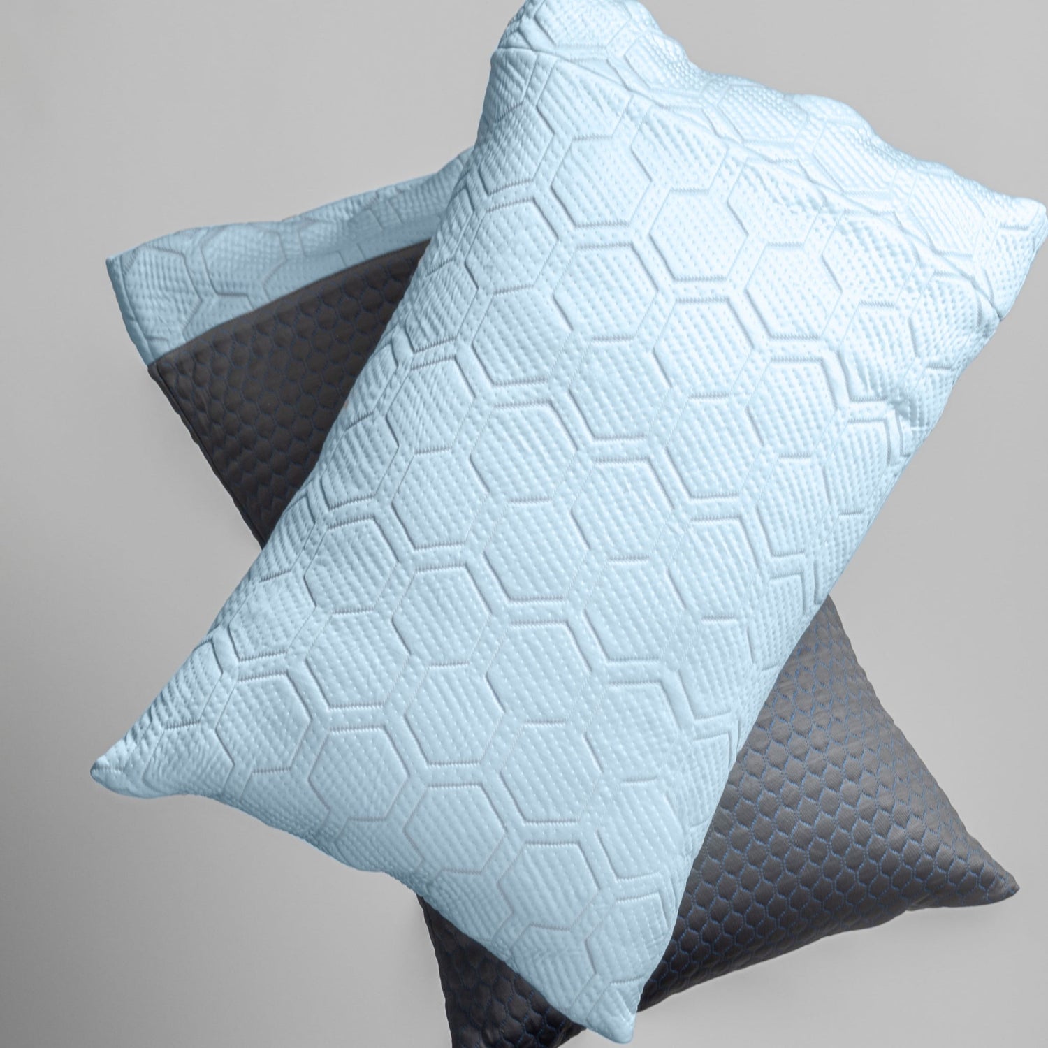 Two textured pillows, one light blue and one gray, on a neutral background