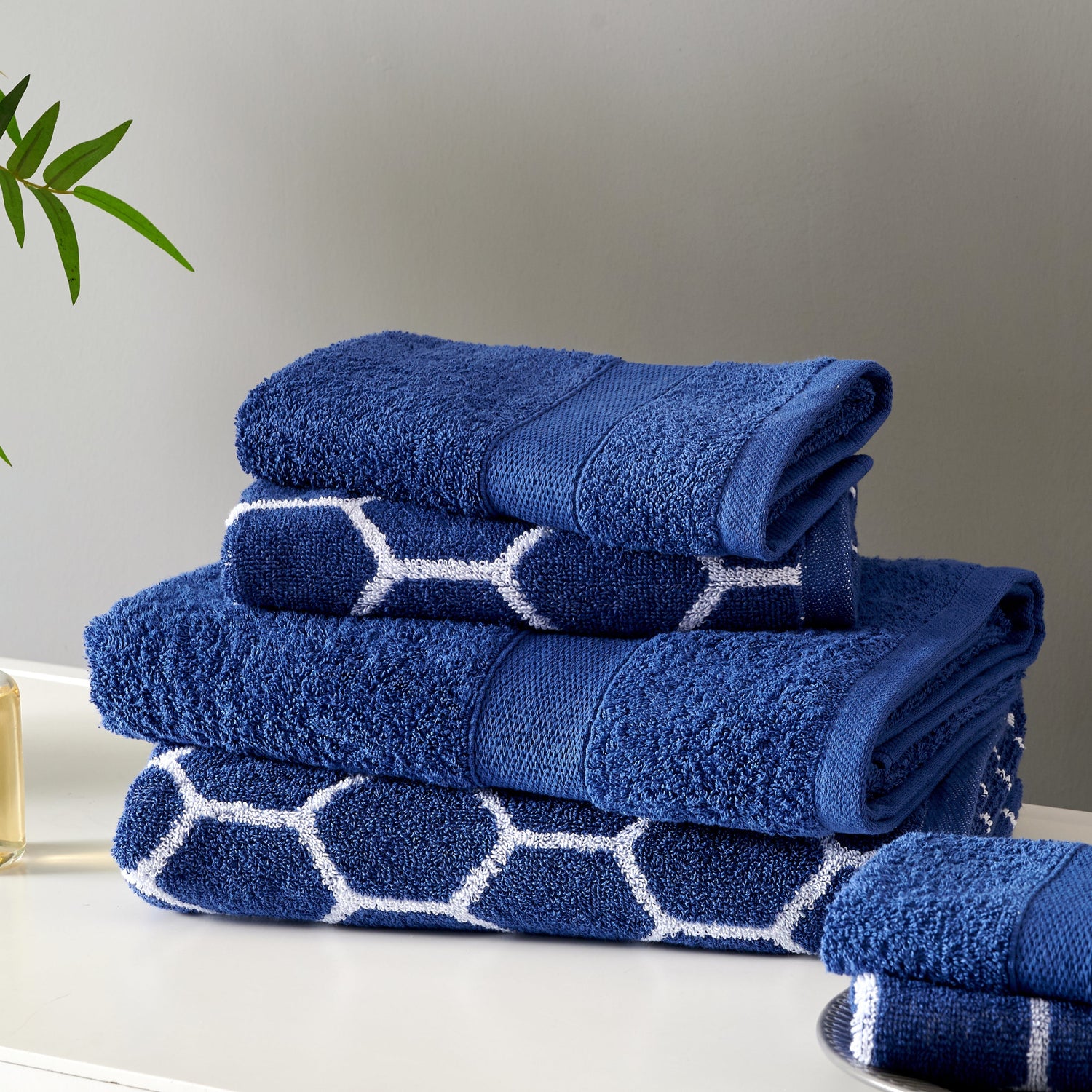 Stack of blue towels with white patterns on a neutral background