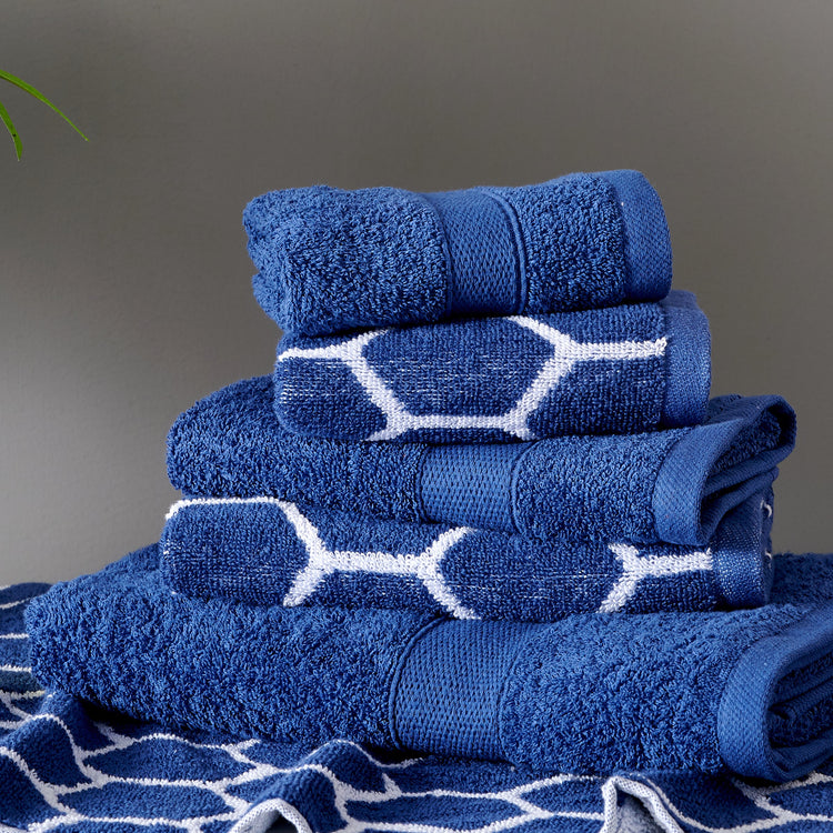 Stack of blue towels with white patterns on a gray background