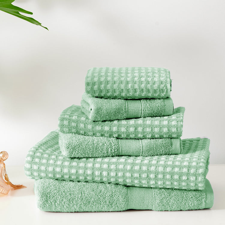 Stack of green towels on a white surface with a minimal background