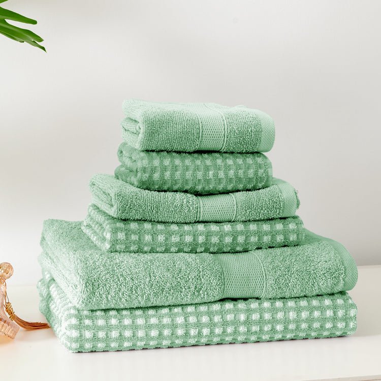 Stack of green towels on a white surface with a light gray background