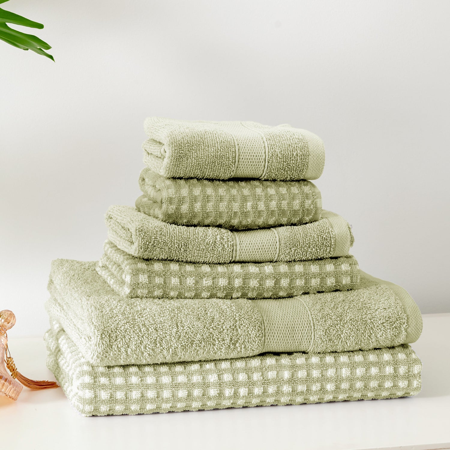 Stack of green towels on a white surface with a light gray background