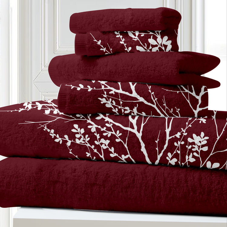 Stack of burgundy towels with white branch patterns on a white background