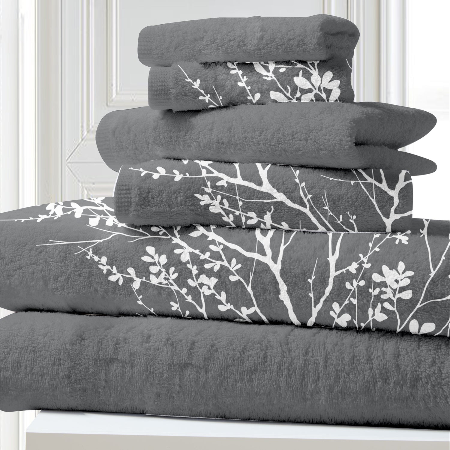 Stack of gray towels with white floral patterns on a white surface.