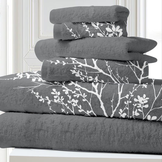 Stack of gray towels with white floral patterns on a white surface.