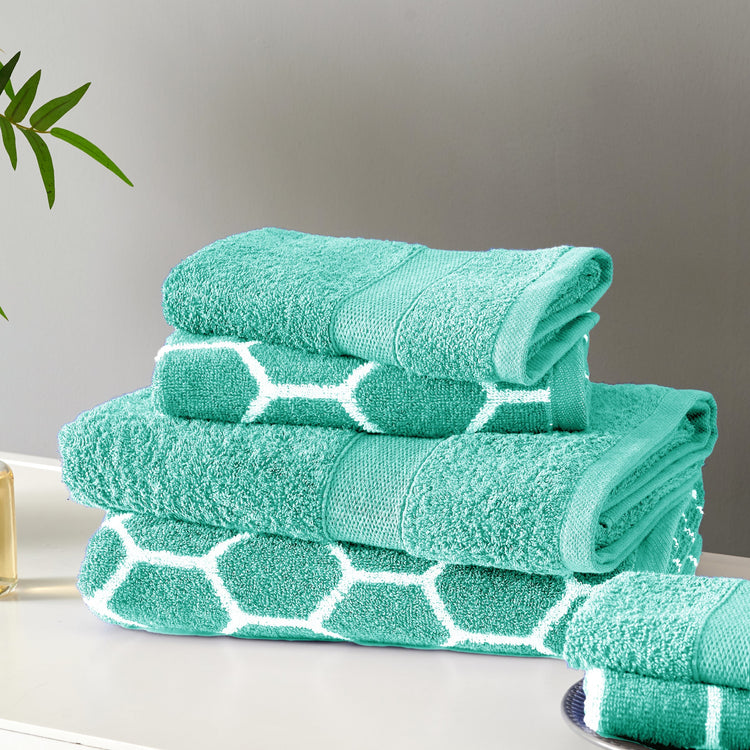 Stack of green towels with white patterns on a neutral background
