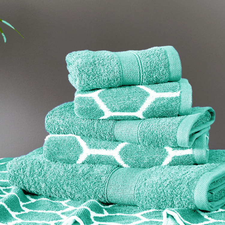 Stack of teal towels with white patterns on a dark background