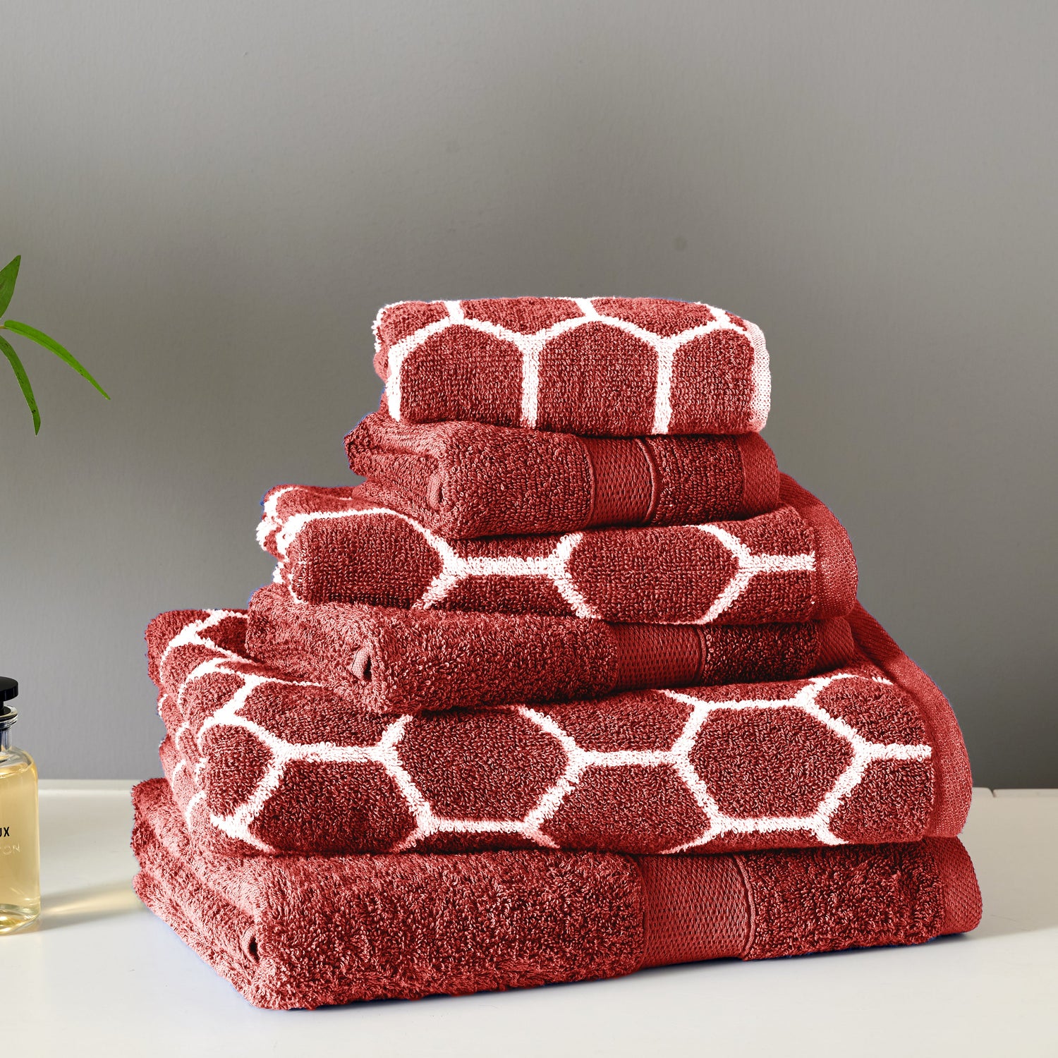 Stack of red towels with white geometric patterns on a gray background