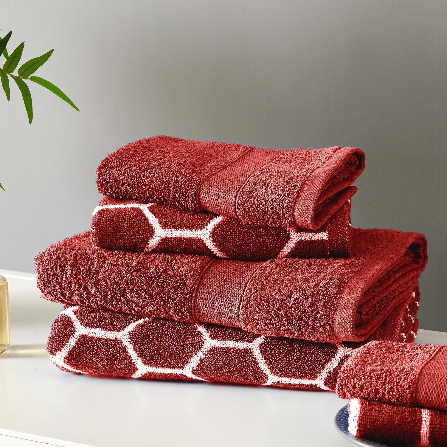 Stack of red towels with geometric pattern on a neutral background