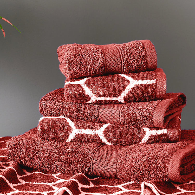 Stack of red towels with white patterns on a dark background