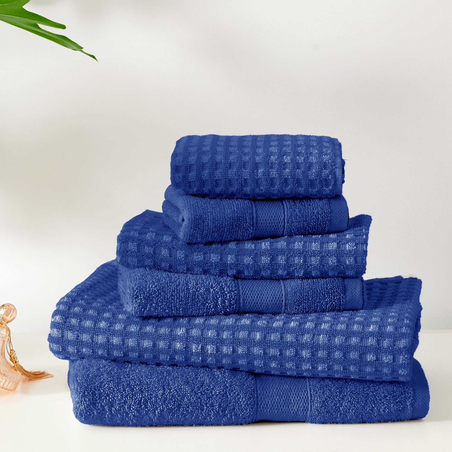 Set of blue towels stacked on a white surface with a minimal background