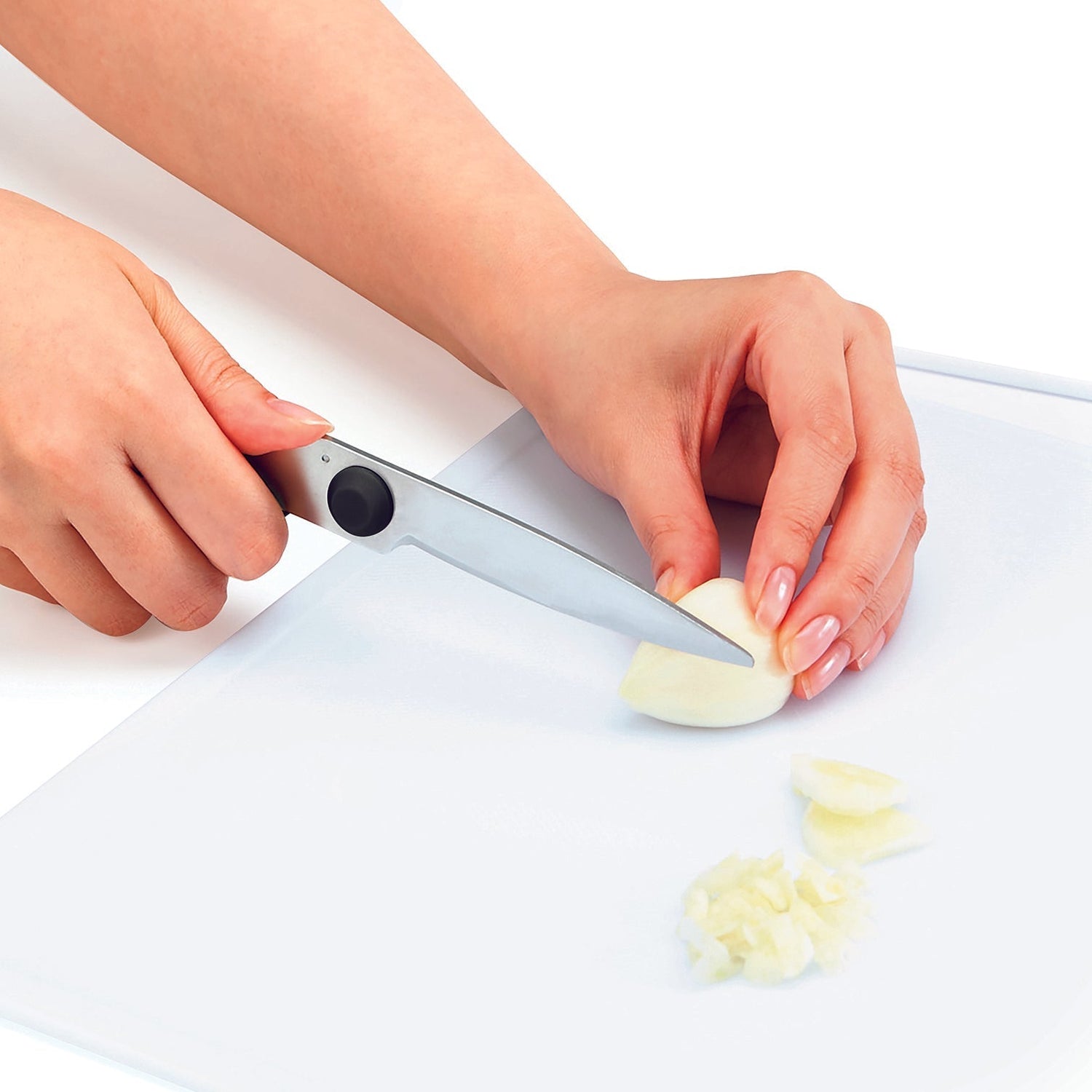 Person using a garlic press to crush garlic on a cutting board.