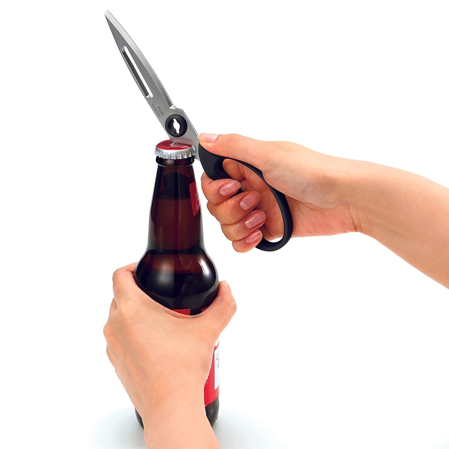 Person using a pair of scissors to open a beer bottle on a white background