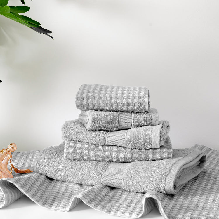 Stack of gray towels on a white surface with a light gray background