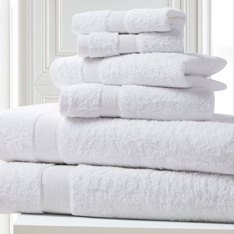 Stack of white towels on a white surface with a light gray wall background