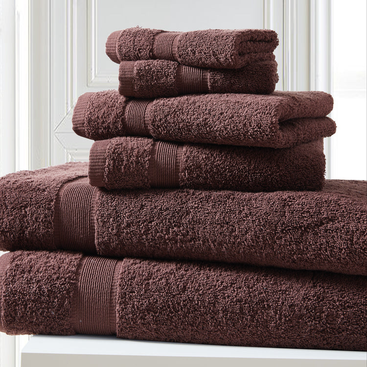 Stack of brown towels on a white surface with a light gray wall background