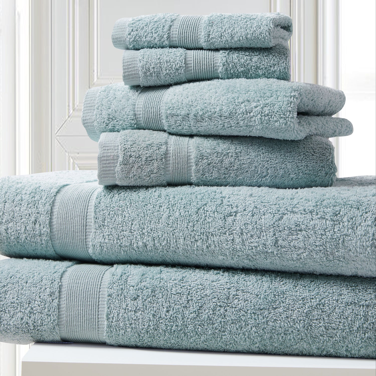 Stack of light blue towels on a white surface with a neutral background