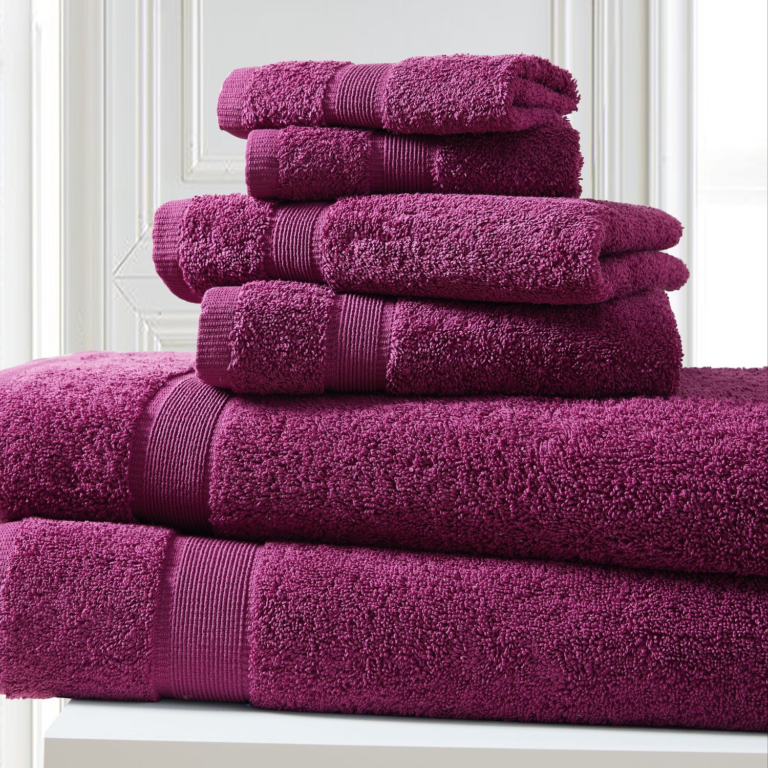 Stack of purple towels on a white surface with a light gray wall background