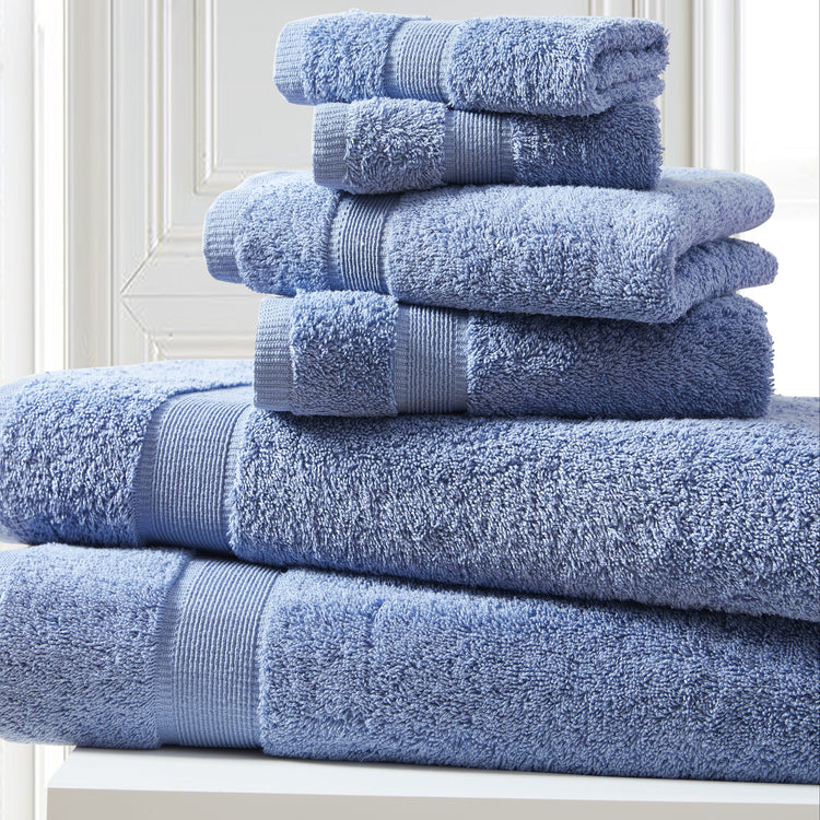 Stack of blue towels on a white surface with a light gray wall background