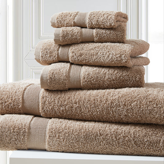 Stack of beige towels on a white surface with a light gray wall background