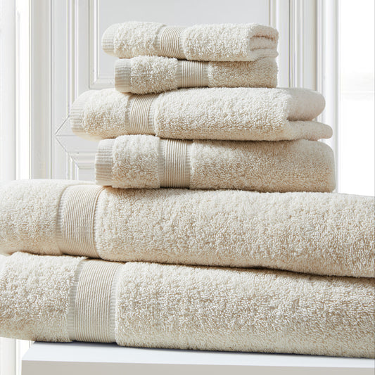 Stack of beige towels on a white surface with a light gray wall in the background