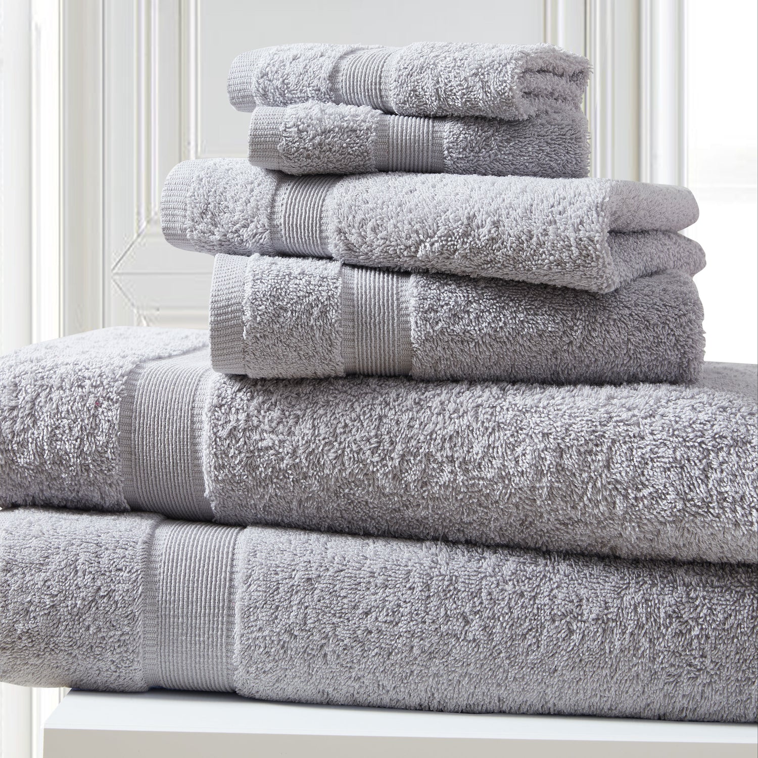 Stack of gray towels on a white surface with a light background