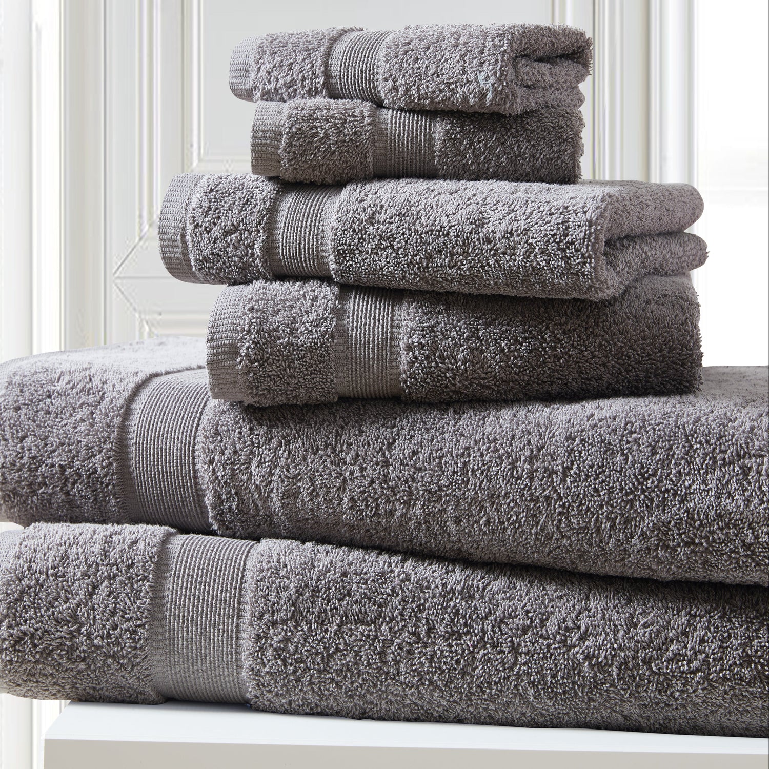 Stack of gray towels on a white surface with a light background
