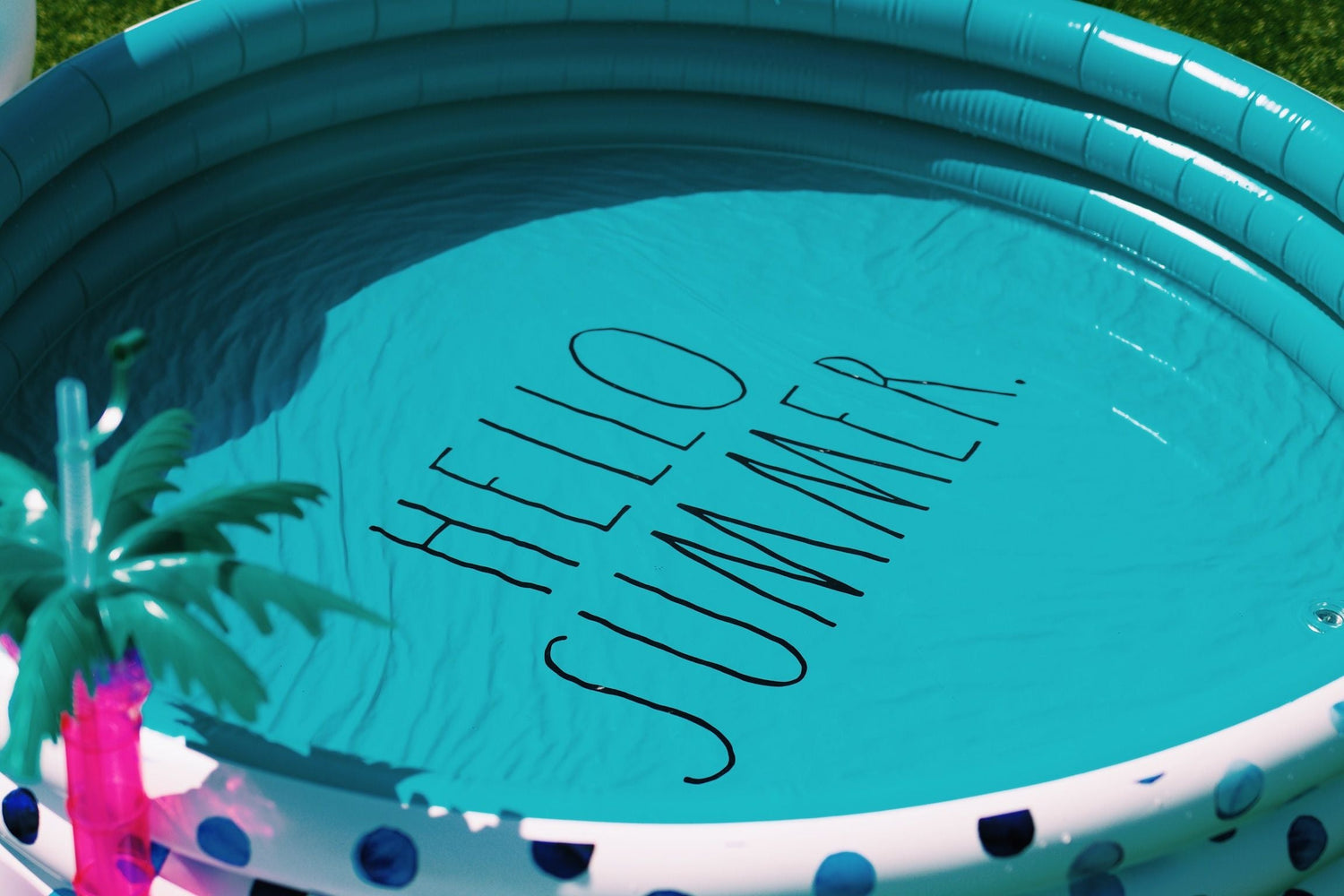 Inflatable pool with 'Hello Summer' text and palm tree decoration.