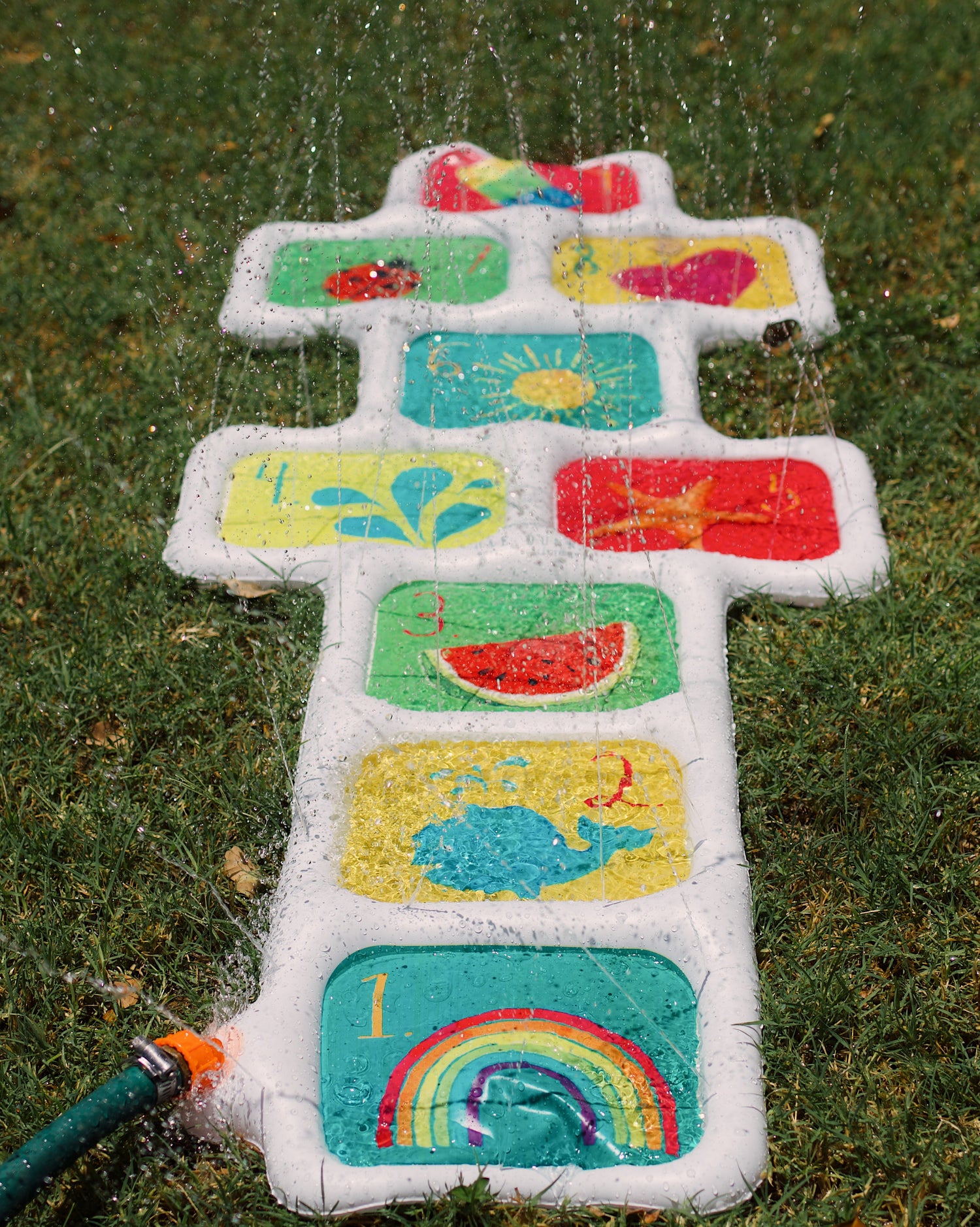 Colorful children's sprinkler with various designs on a grassy background