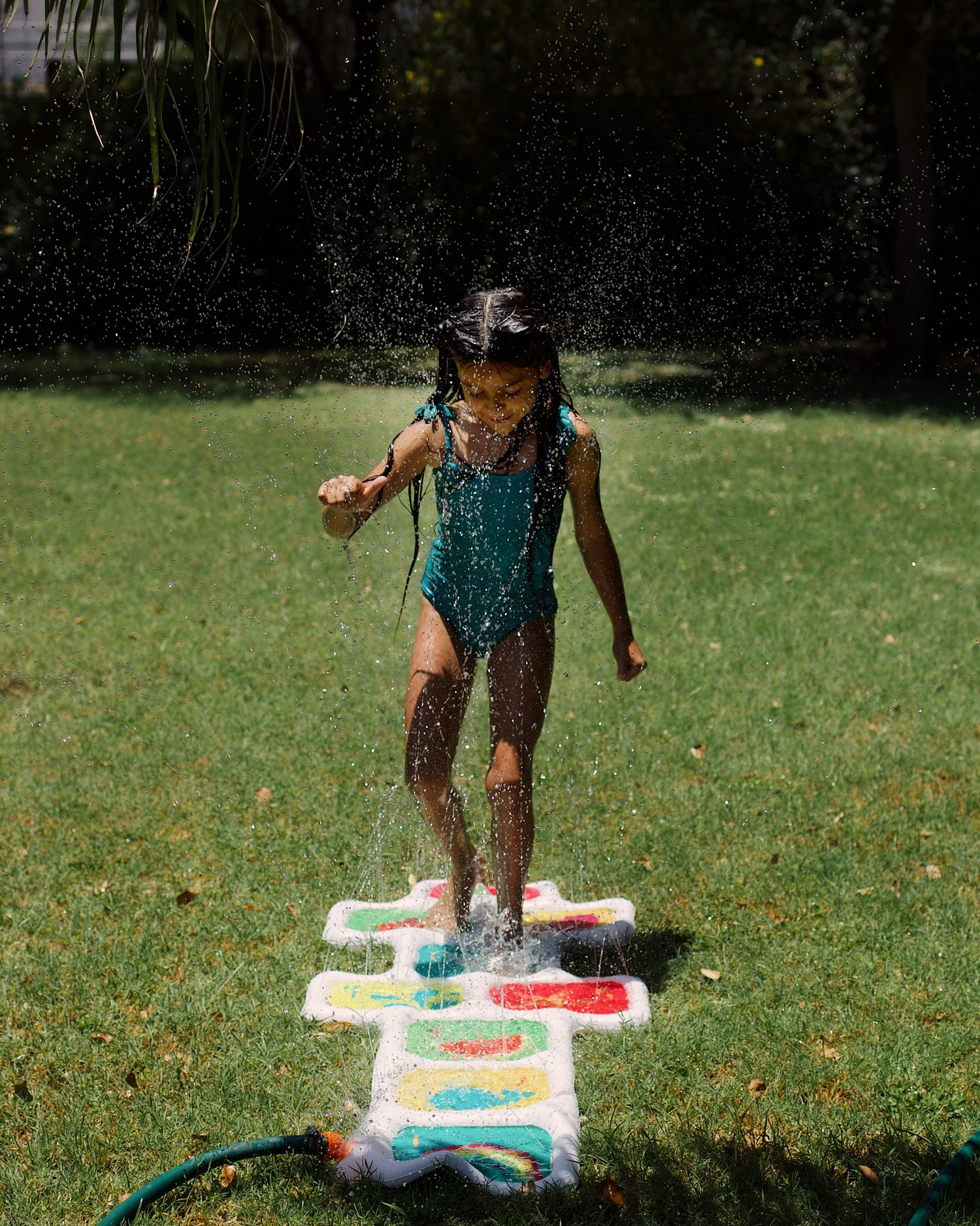 Child playing with a water sprinkler on a grassy area