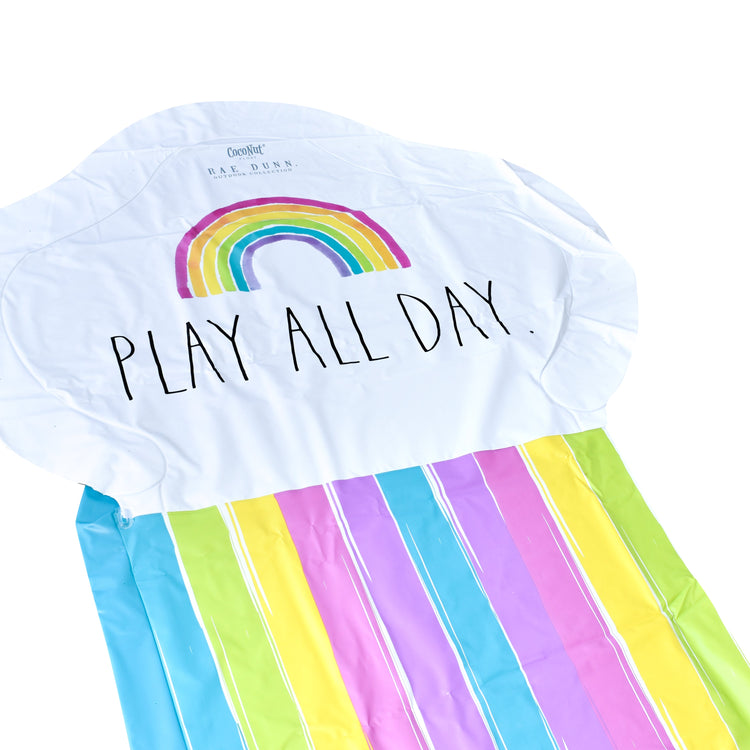 White t-shirt with rainbow and 'PLAY ALL DAY.' text, paired with a colorful striped towel.