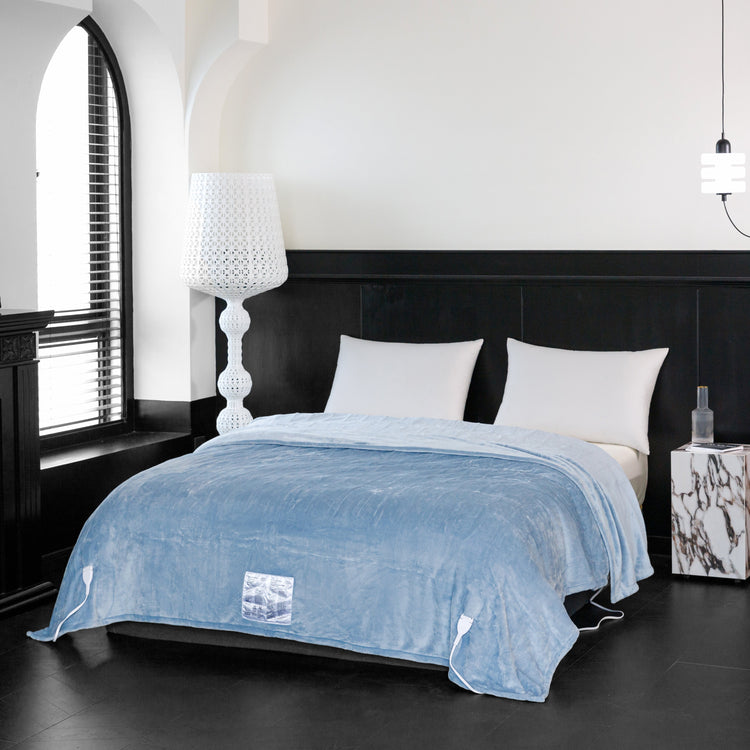 Blue blanket on a bed in a modern bedroom with white walls and black furniture.