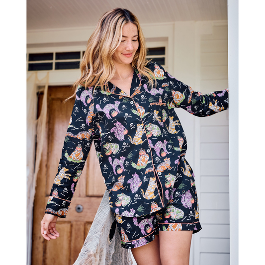 Woman wearing a black pajama top with colorful cat pattern outdoors.
