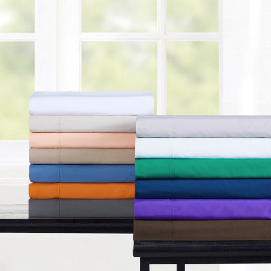 Bed with gray bedding and pillows in a room with large windows.