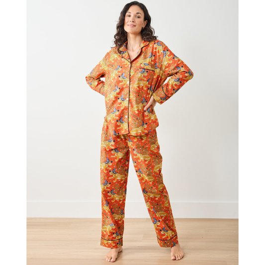 Woman wearing a patterned orange pajama set against a plain background