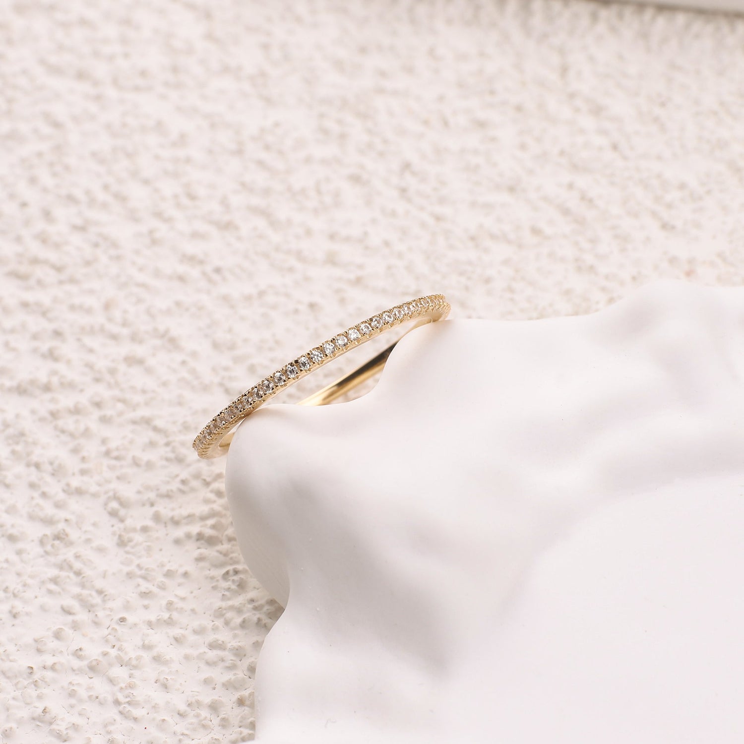 Gold ring with small diamonds on a white marble surface