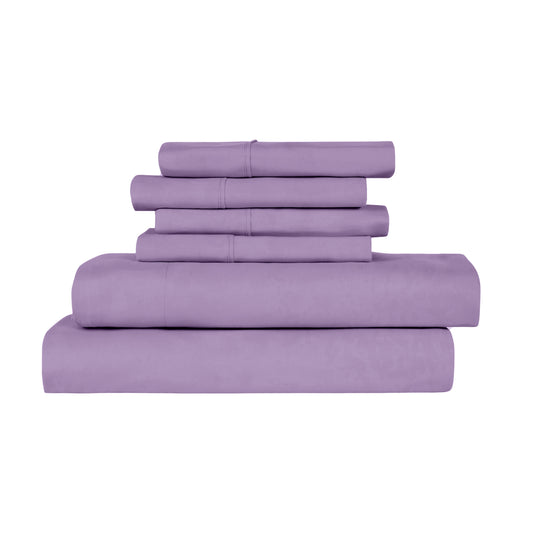 Purple bedding set on a bed in a room with large windows.